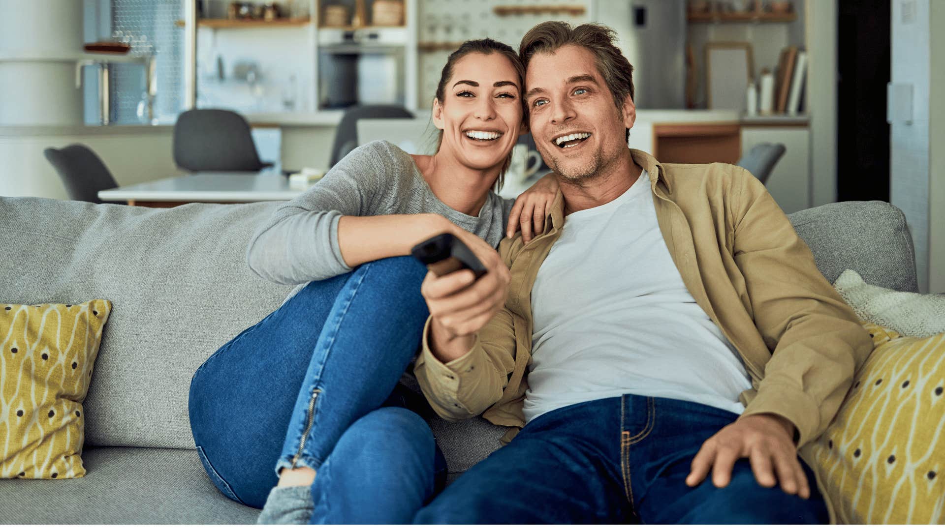 couple watching TV and man using remote to change channel 