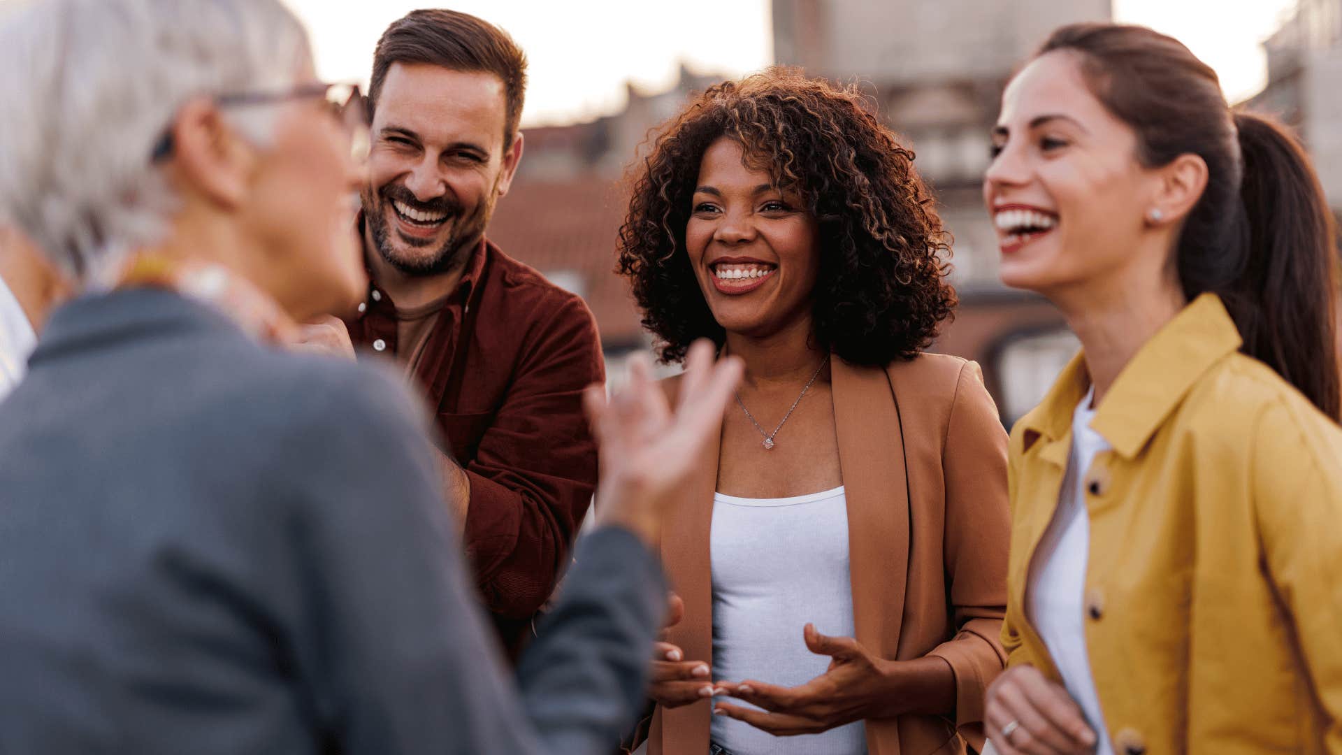 group of young adults talking to older woman 