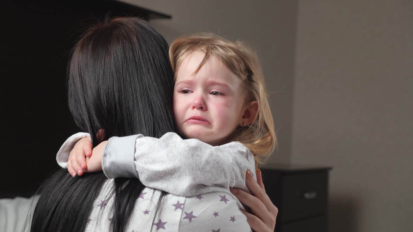 little girl crying hugging her mother