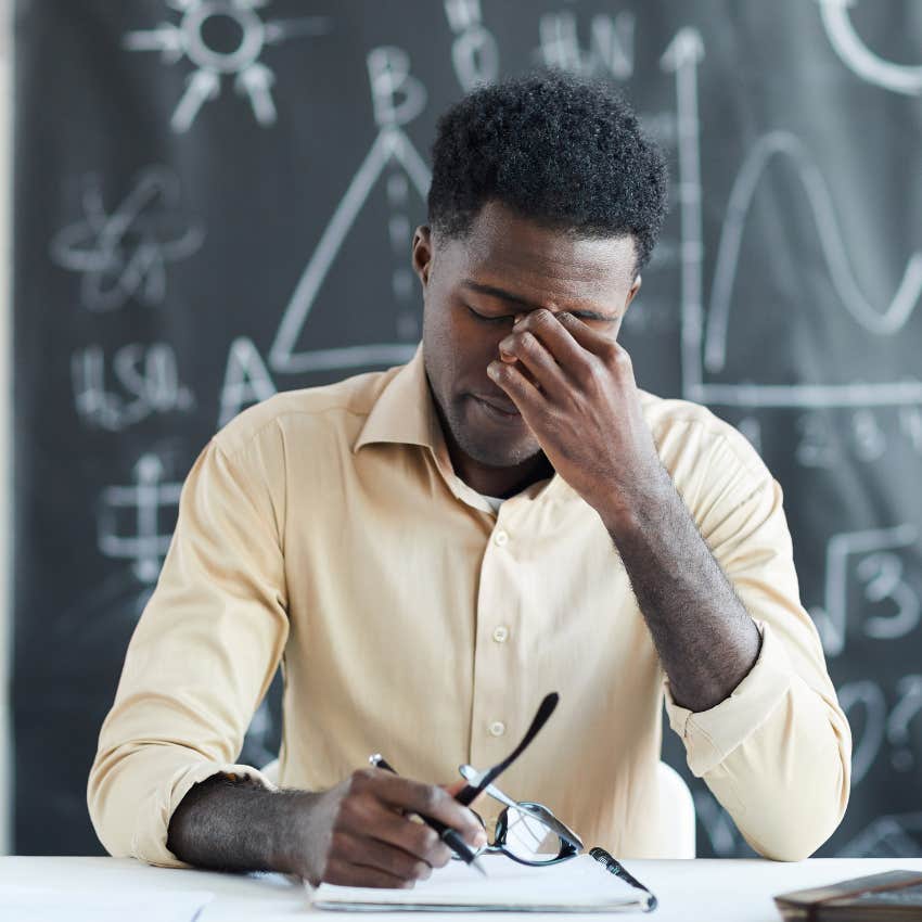 Tired school staff member looking annoyed in his classroom. 