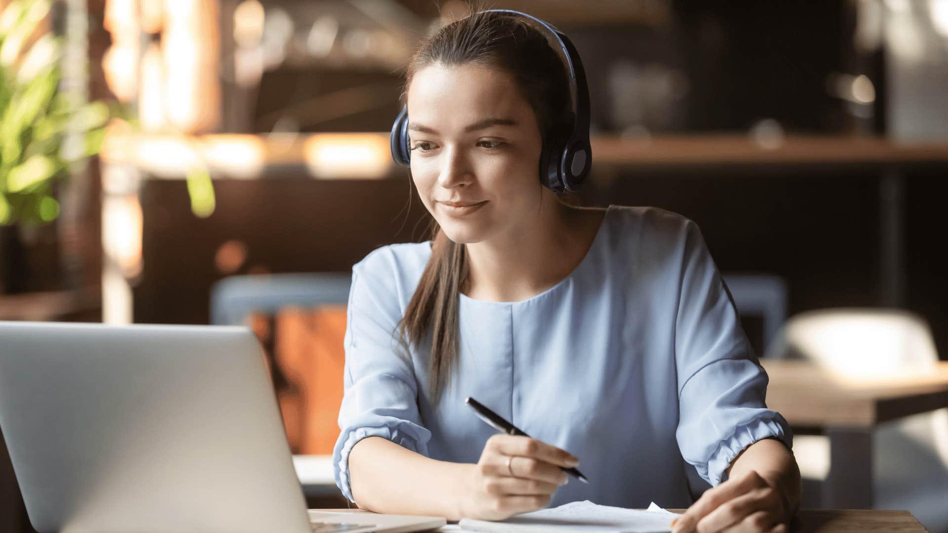 woman listening to video and writing down notes