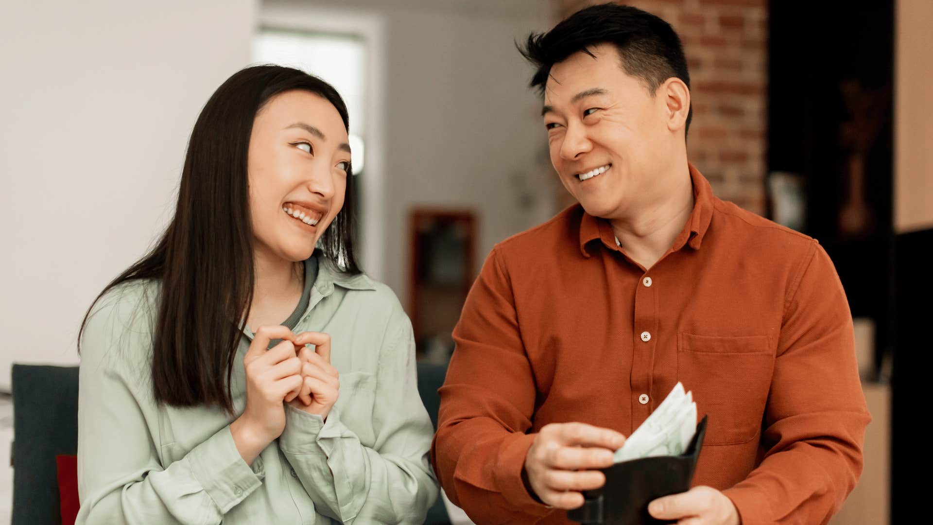 man opening wallet showing woman