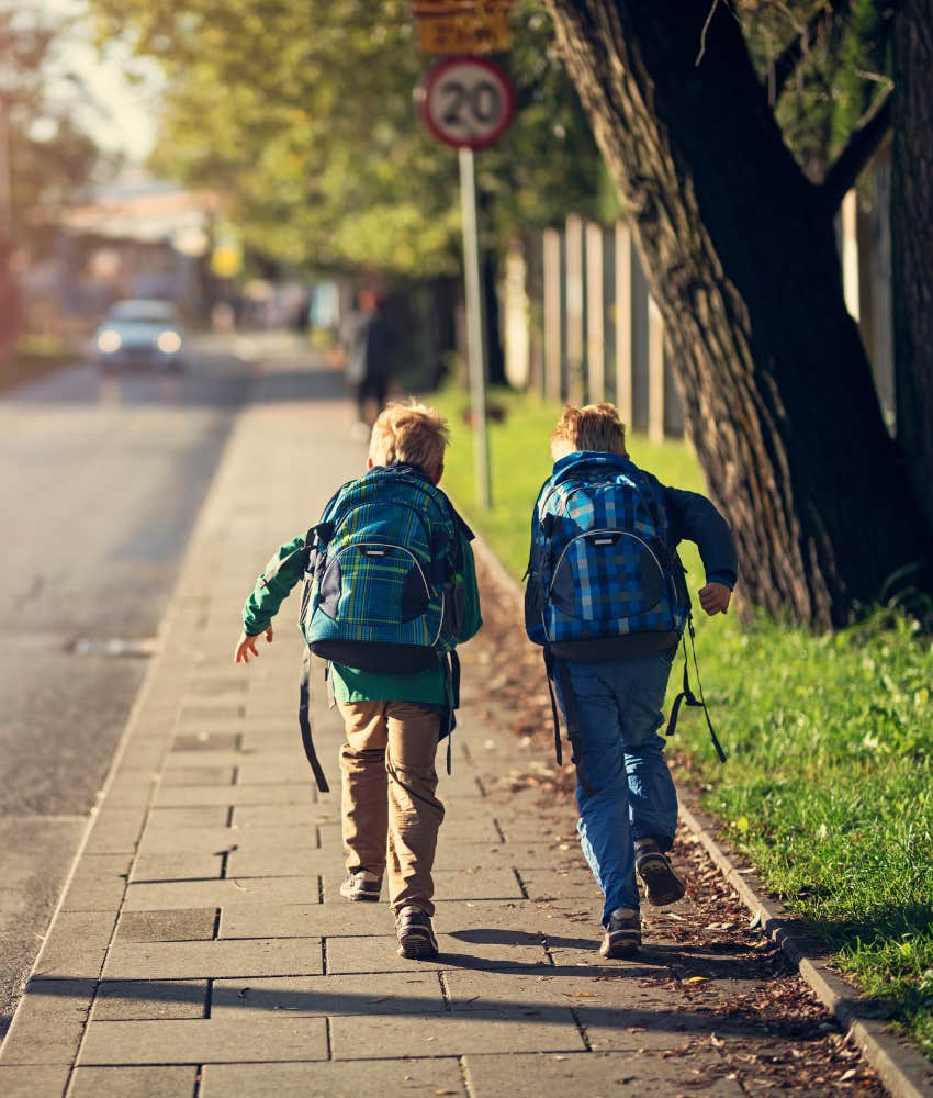 two boys walking home from school on sidewalk