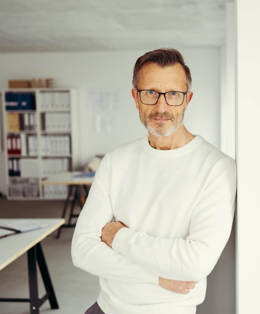 Professional looking man leans against office wall