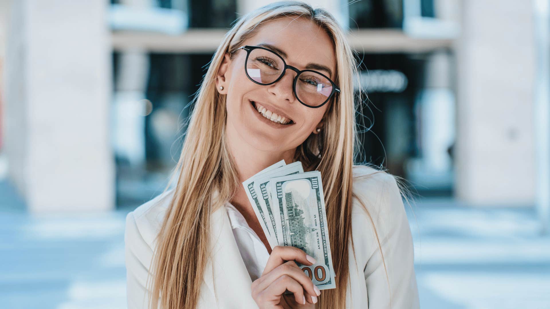 woman holding up money while smiling 