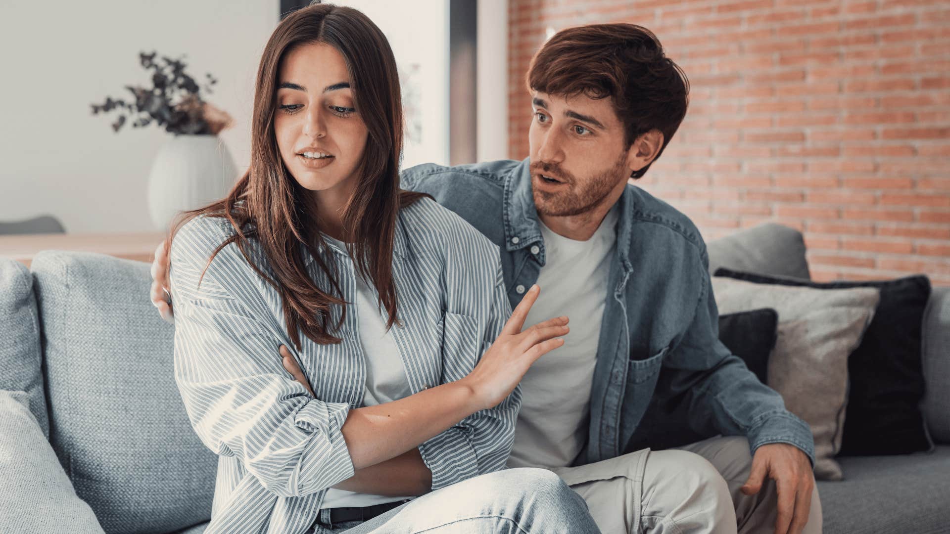 man trying to comfort woman while woman brushes off man 