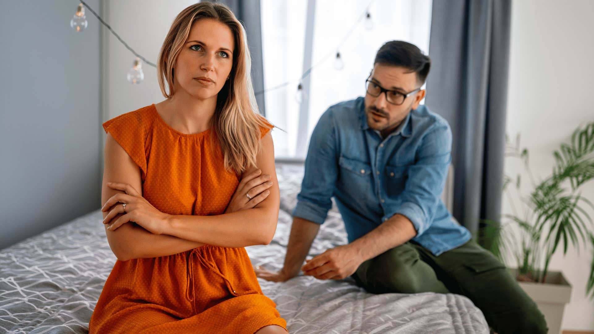 woman ignoring man on bed