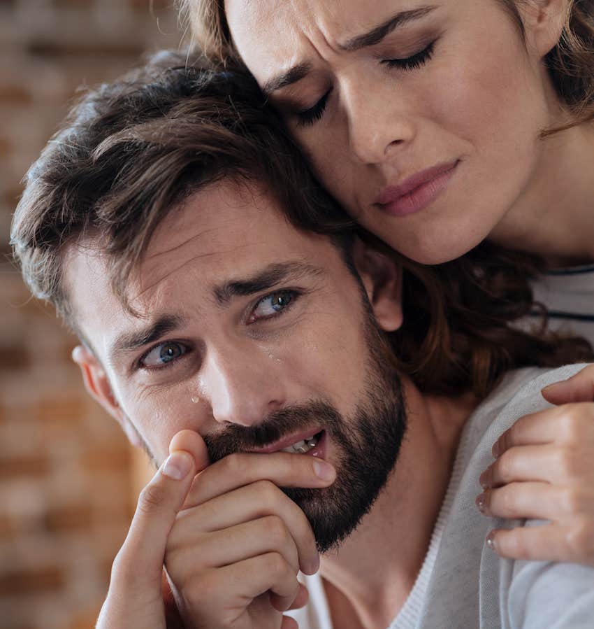 upset man is comforted by caring woman holding his shoulders