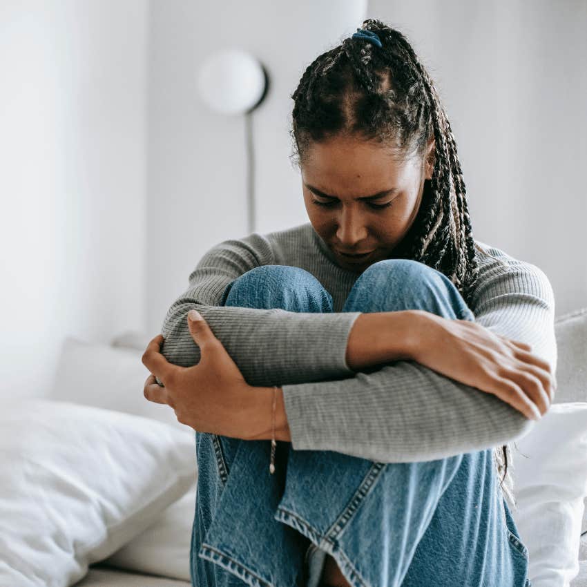 upset woman hugging knees to chest