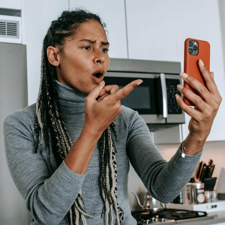 upset woman pointing at phone in hand