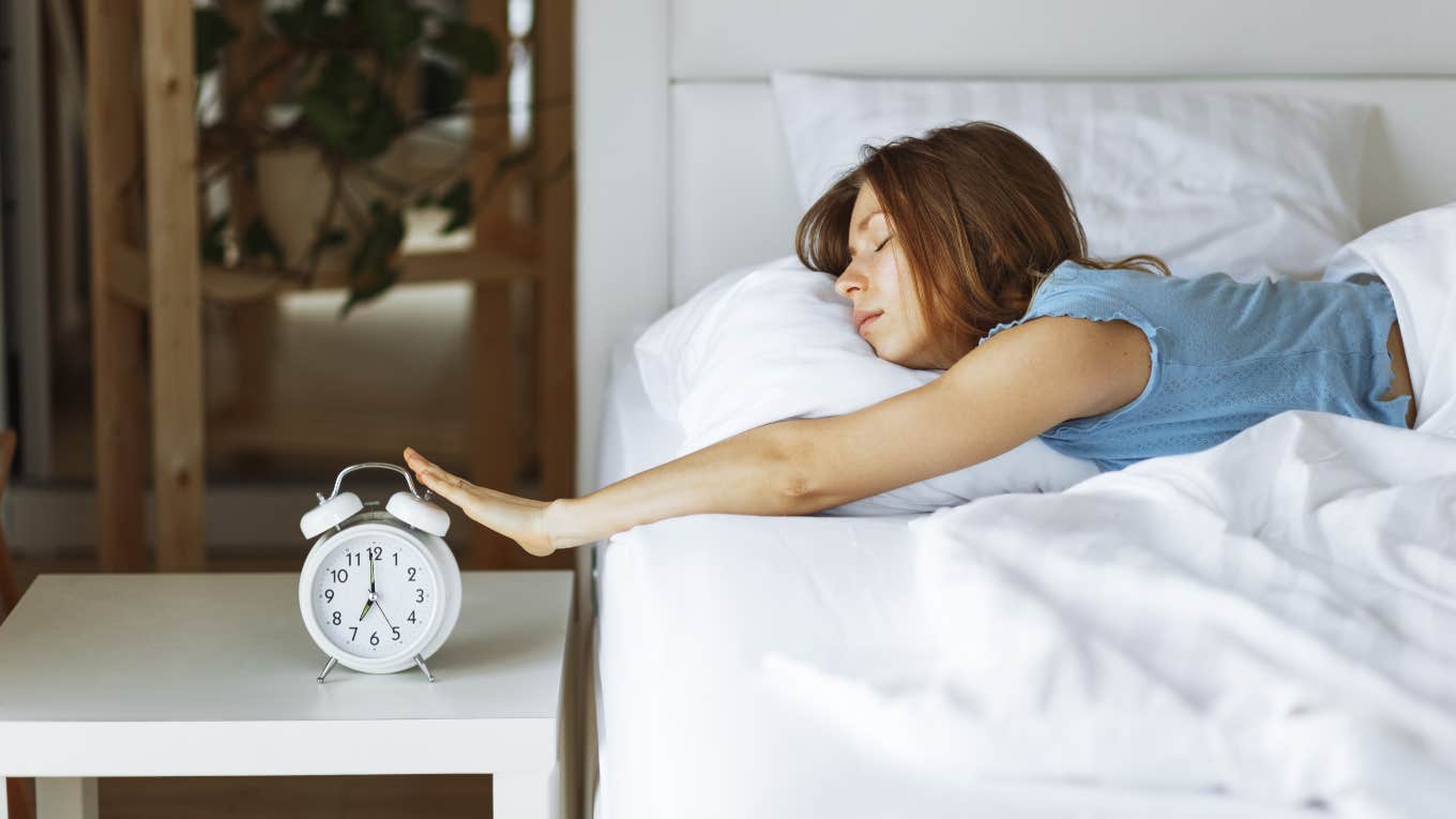 Woman snoozing her alarm in the morning