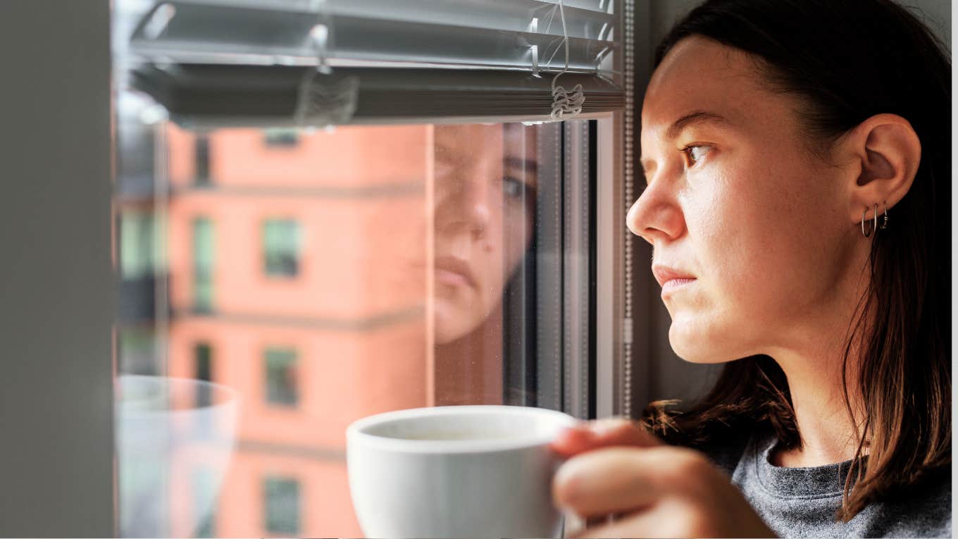 Woman looking out window of home