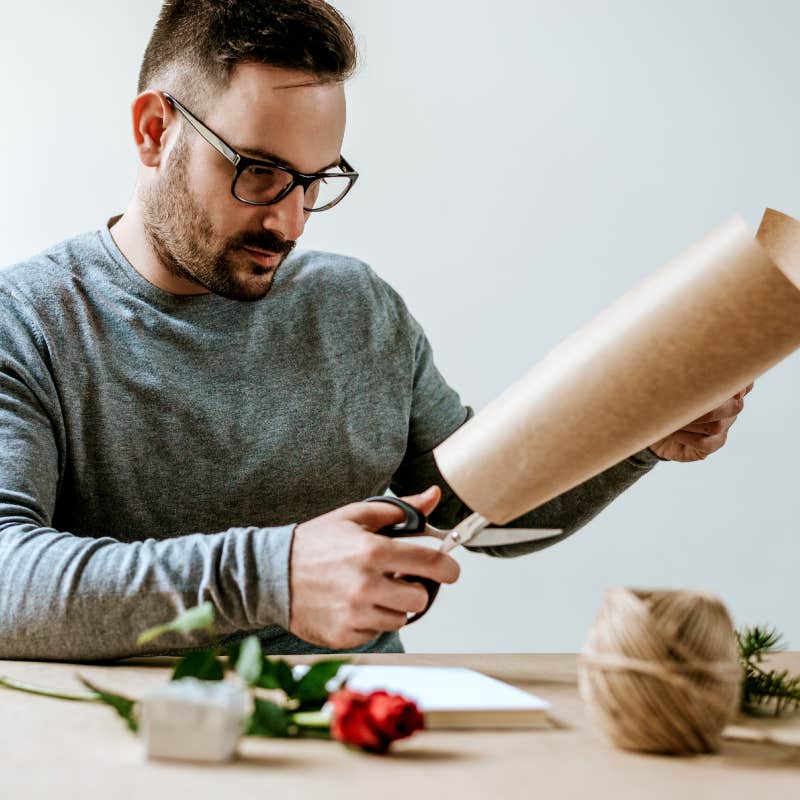 man cutting paper for gifts