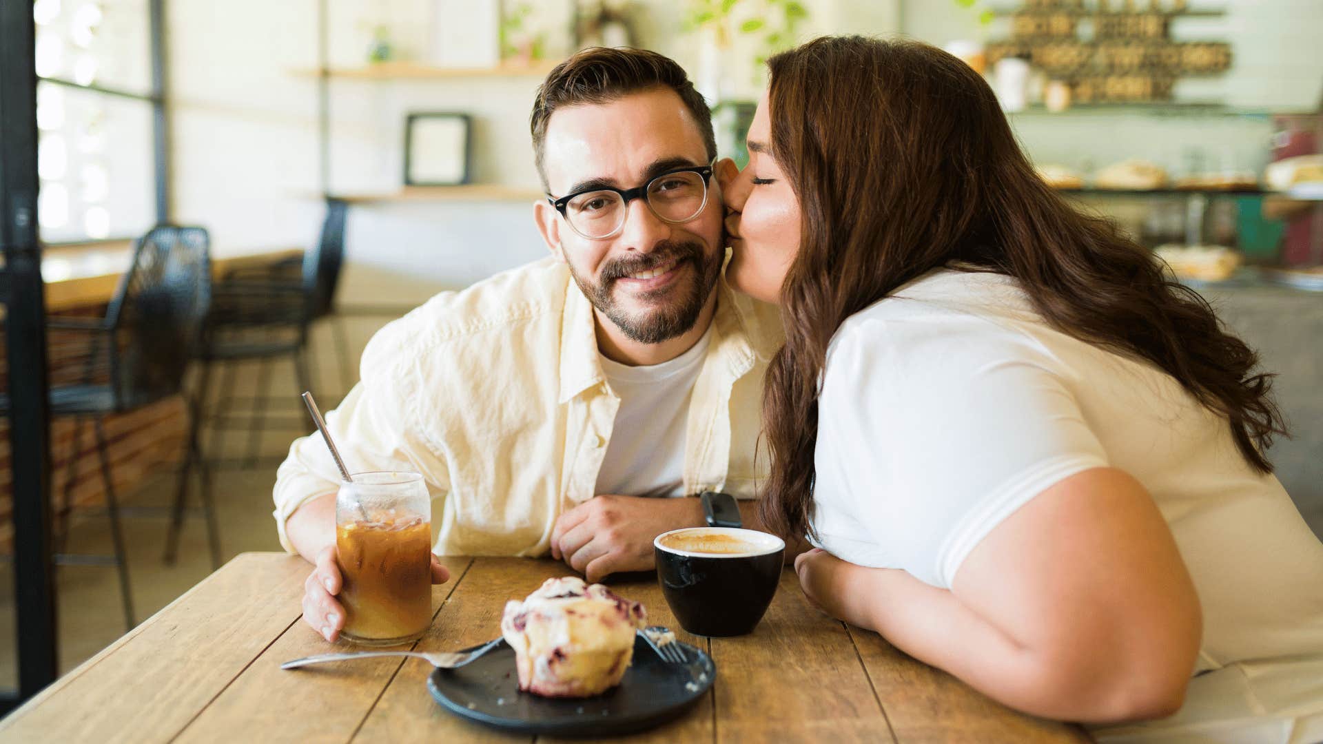 She kisses his cheek after a surprise at cafe