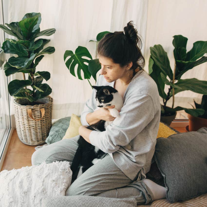 Sad woman with pet debt hugging her cat