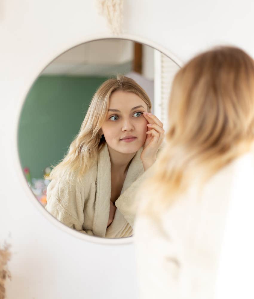 woman examining face in mirror