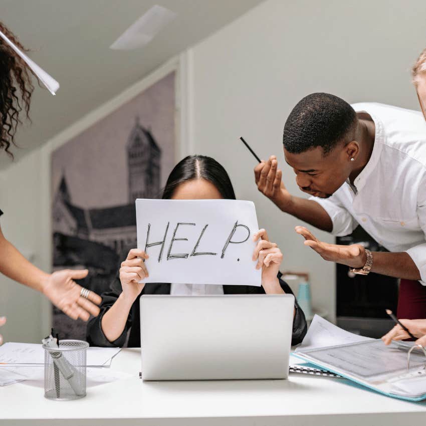 woman holding up help sign in chaotic workplace