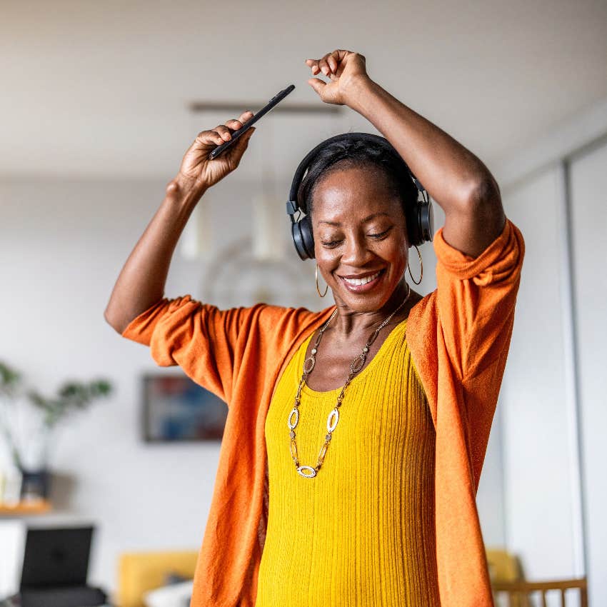 Joyful woman listening to music and dancing