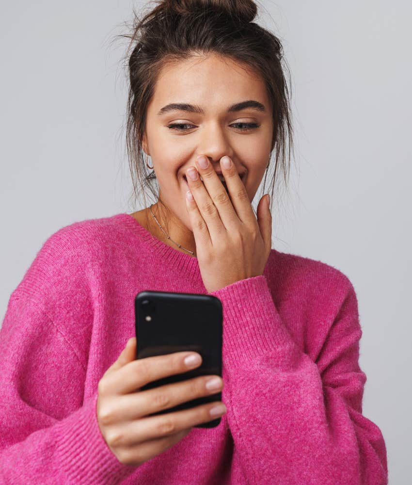 woman laughing while scrolling Facebook