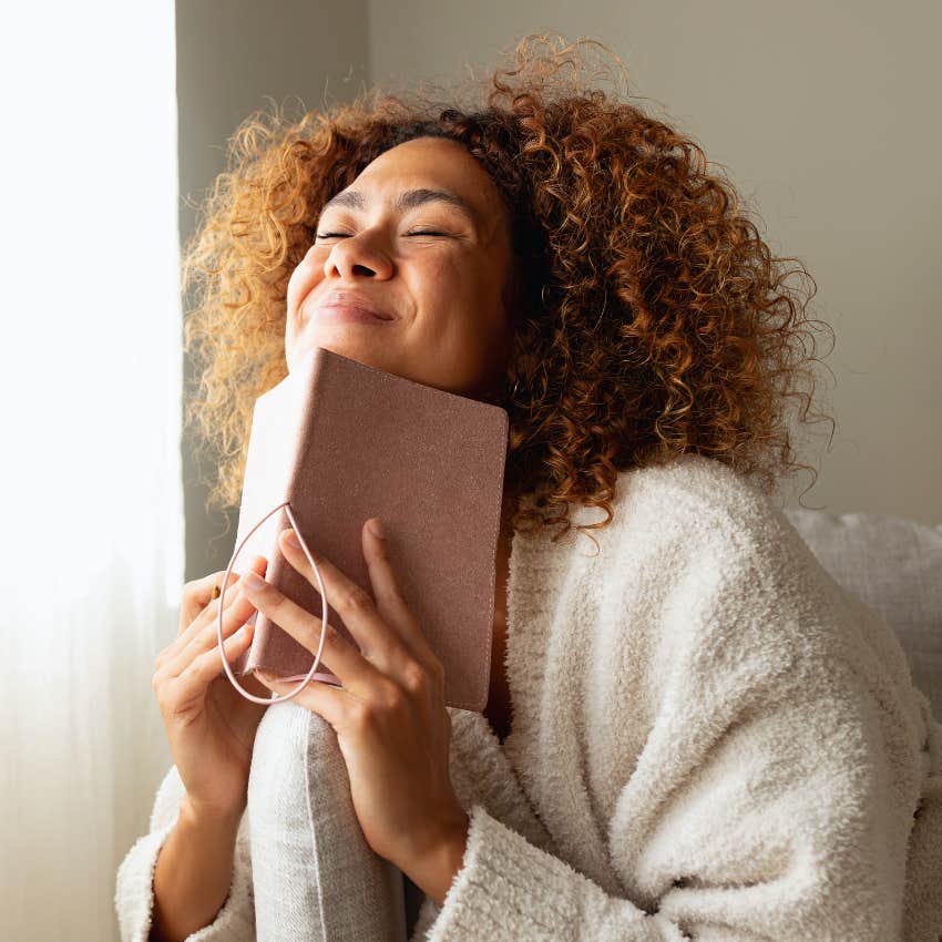 Mentally tough woman smiling with her manifestation journal. 