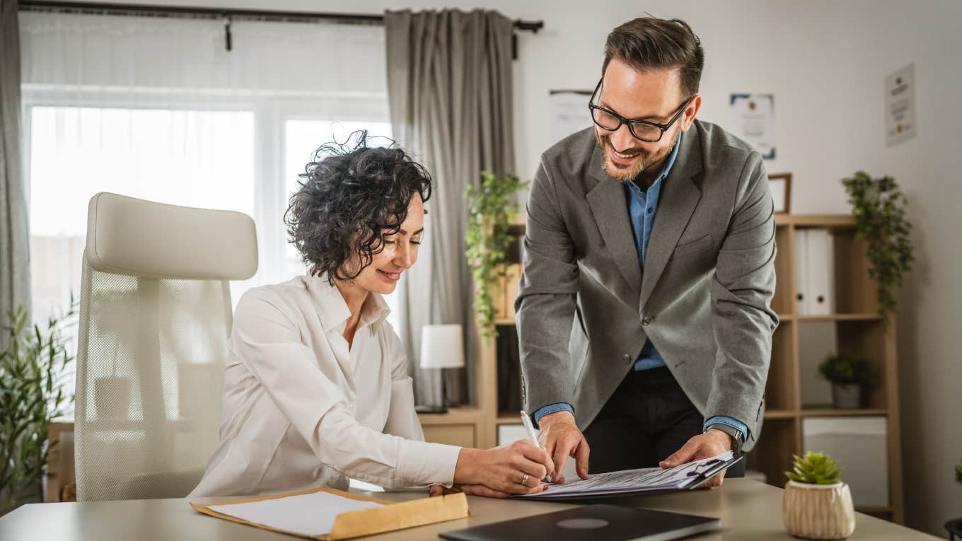 woman signing insurance documents with businessman in office