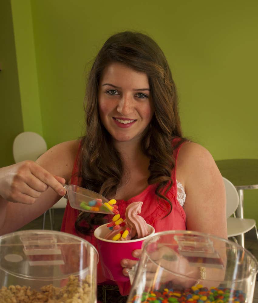 Woman putting toppings on frozen yogurt