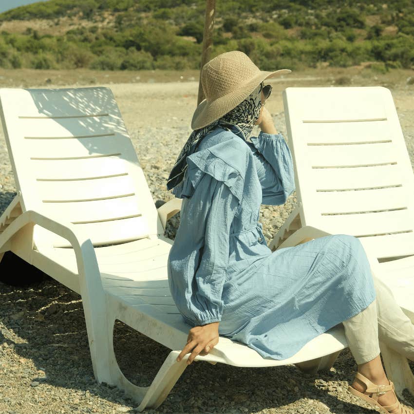 woman sitting on beach chair in sun hat and long sleeve