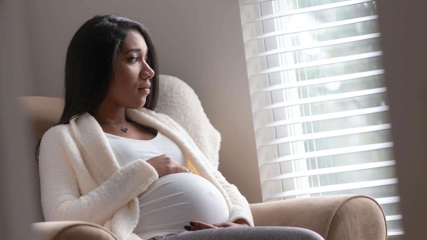 Pregnant woman looking out the window 