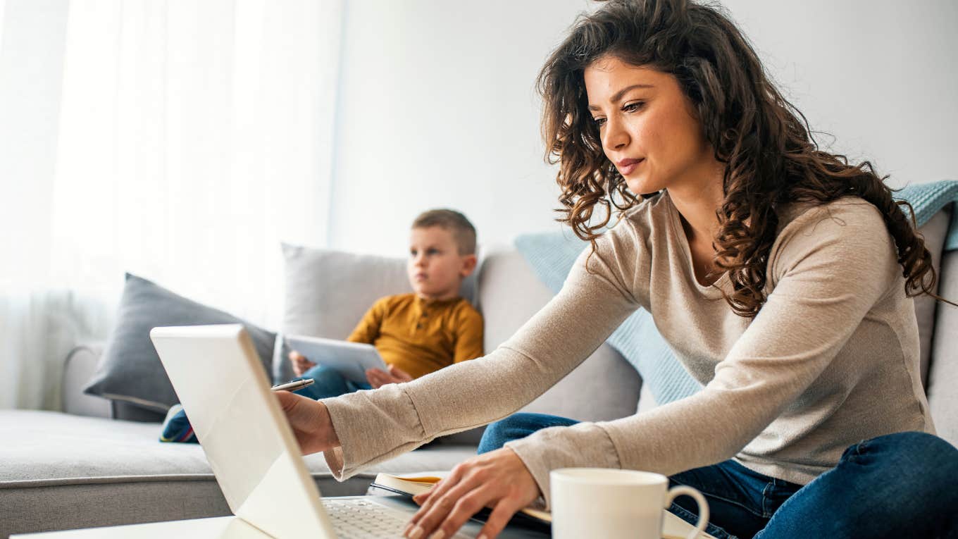 Working mom on her laptop while her kid plays with morning basket. 