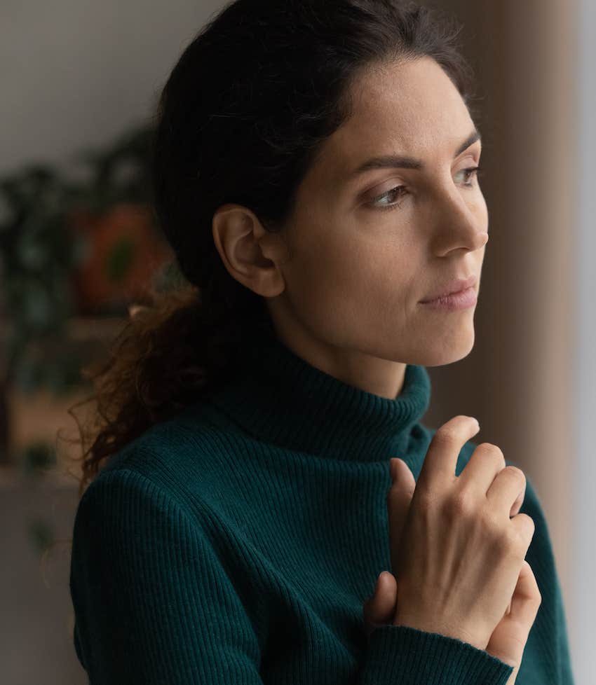 Mournful woman looks out window and knows it was not her fault