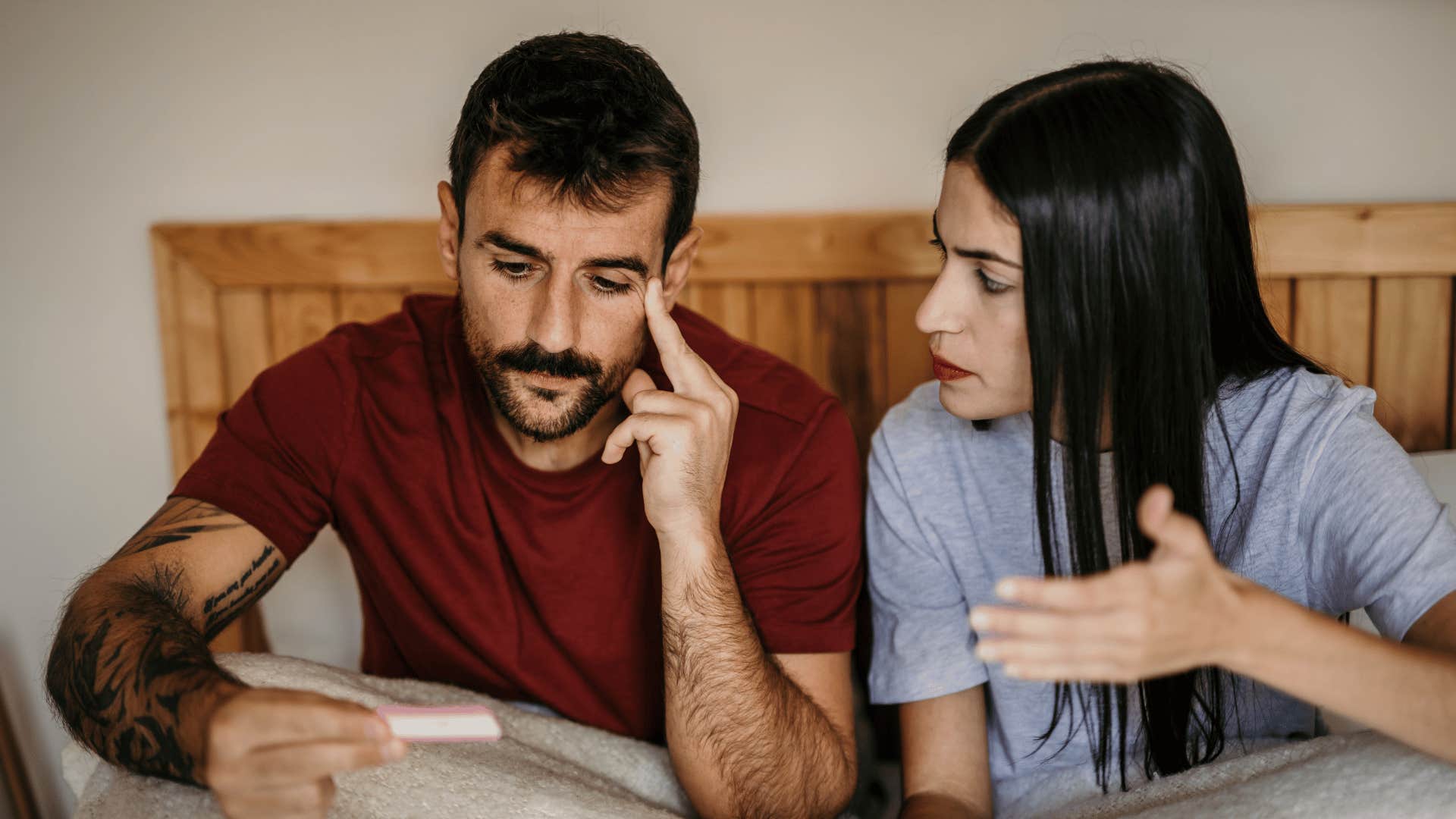 A couple sits in bed and argues