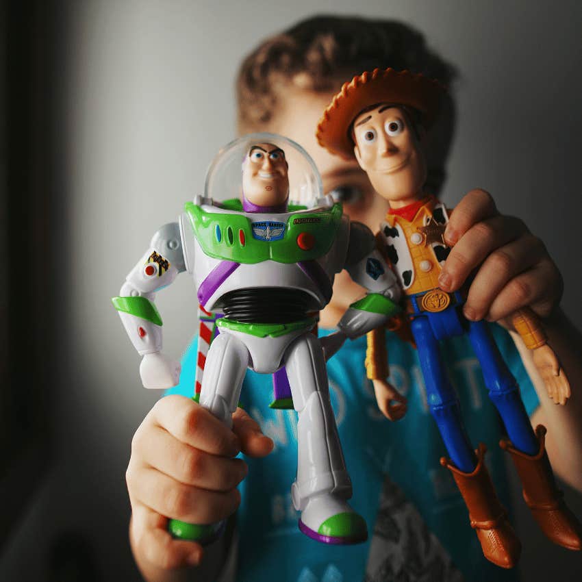 young boy holding buzz and woody toys