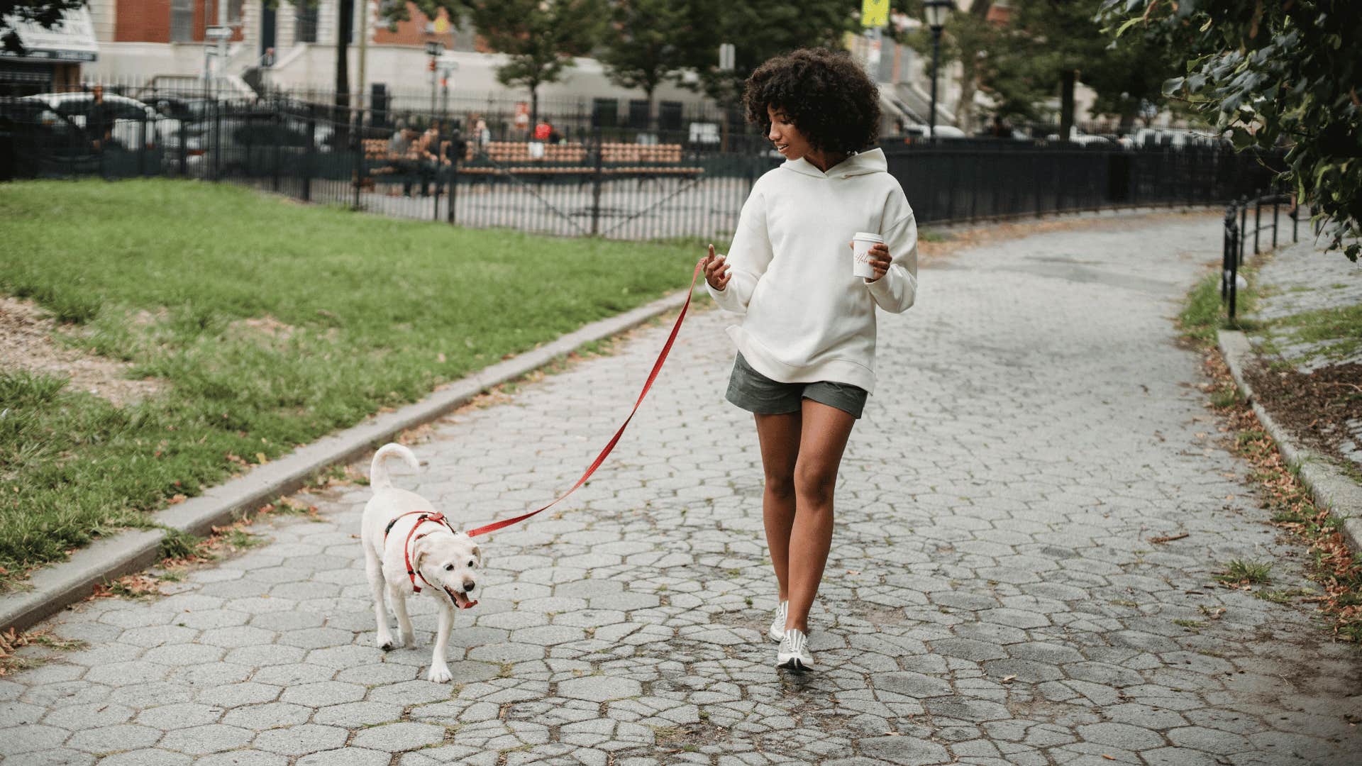 young woman walking dog down a path