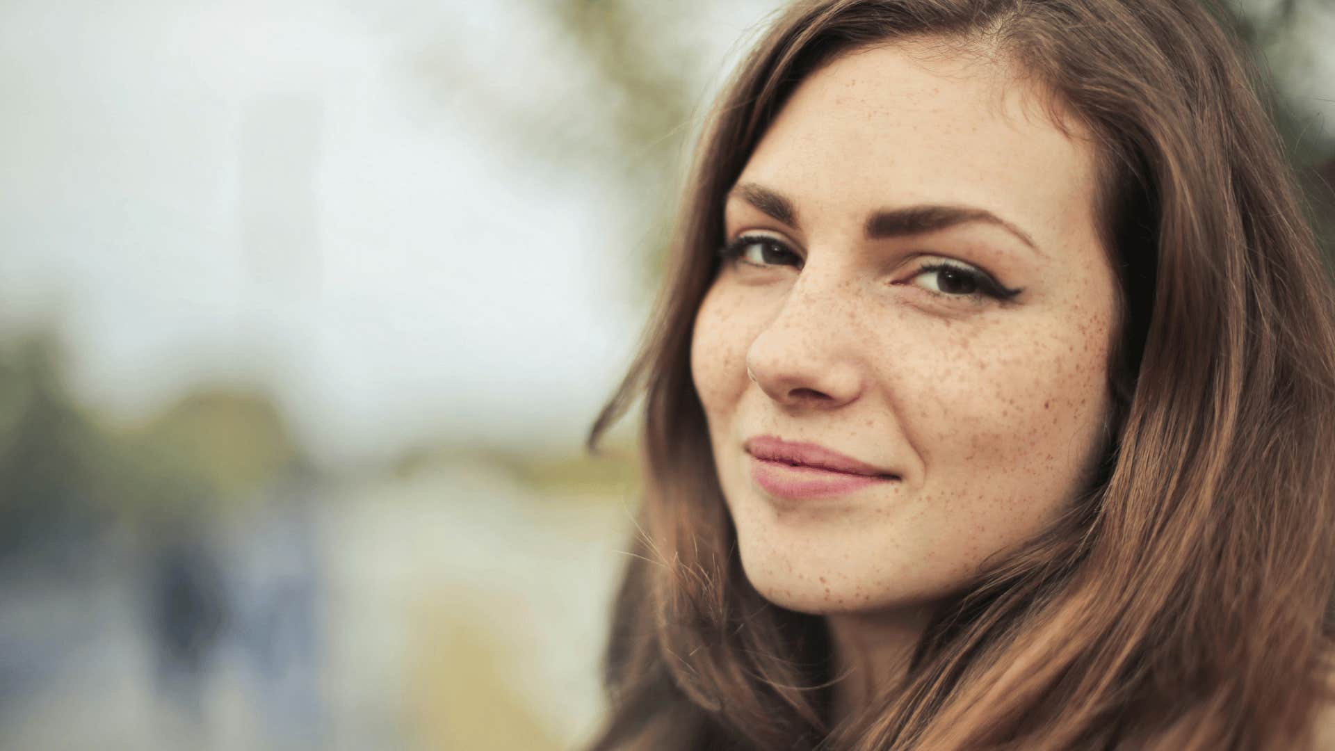 woman with freckles smiling gently