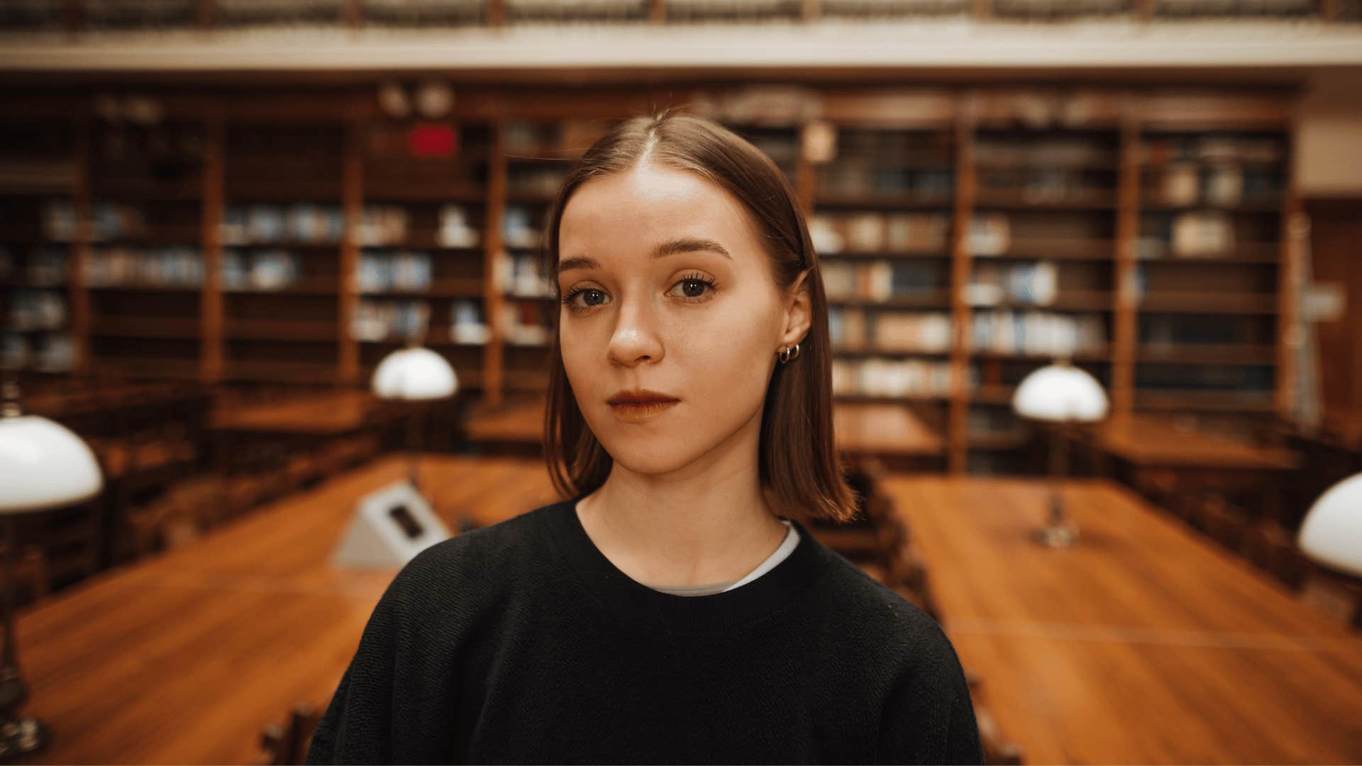 serious young woman standing in the library