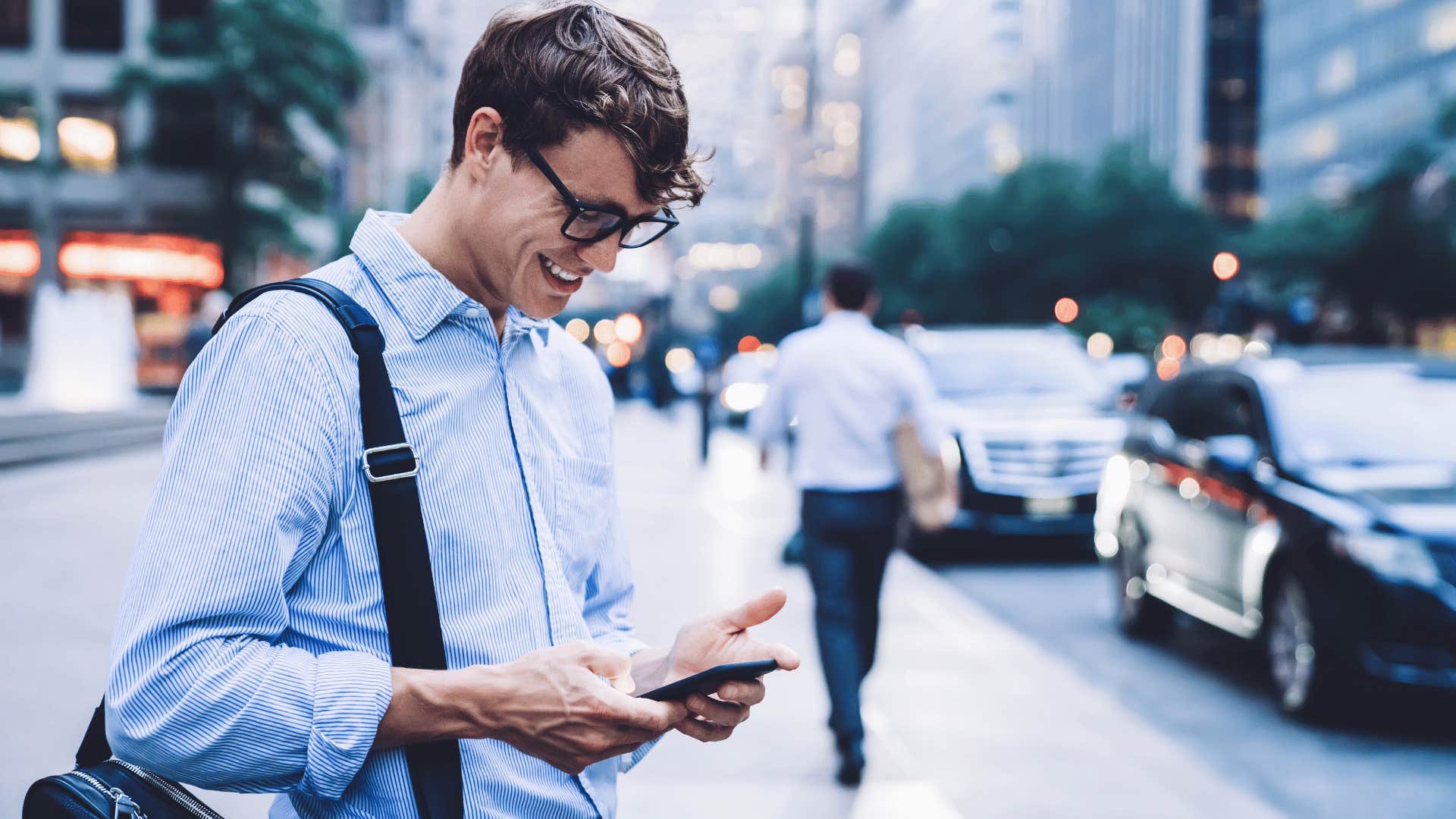 young man smiling down at his phone