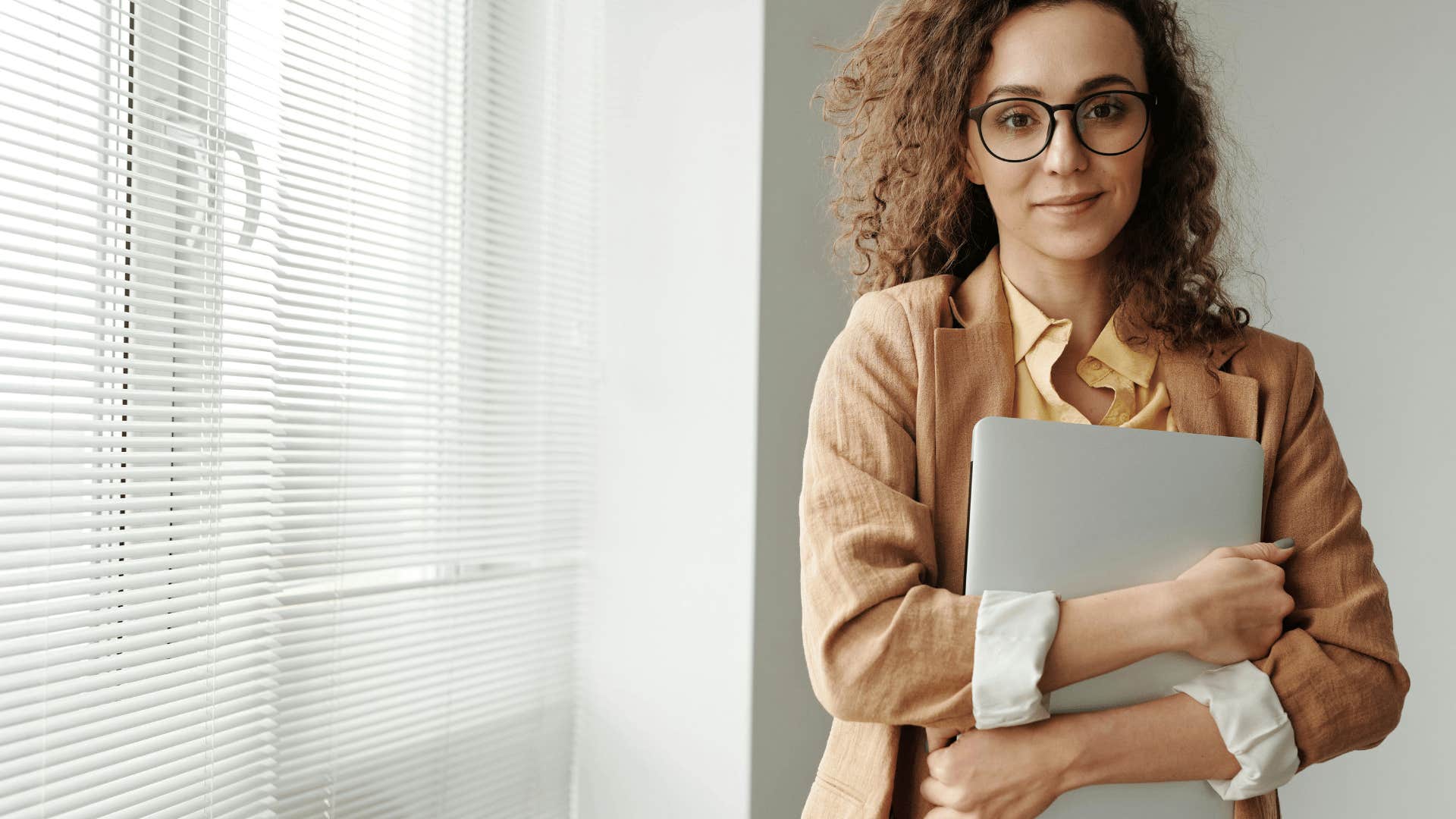 young woman in glasses holding a laptop