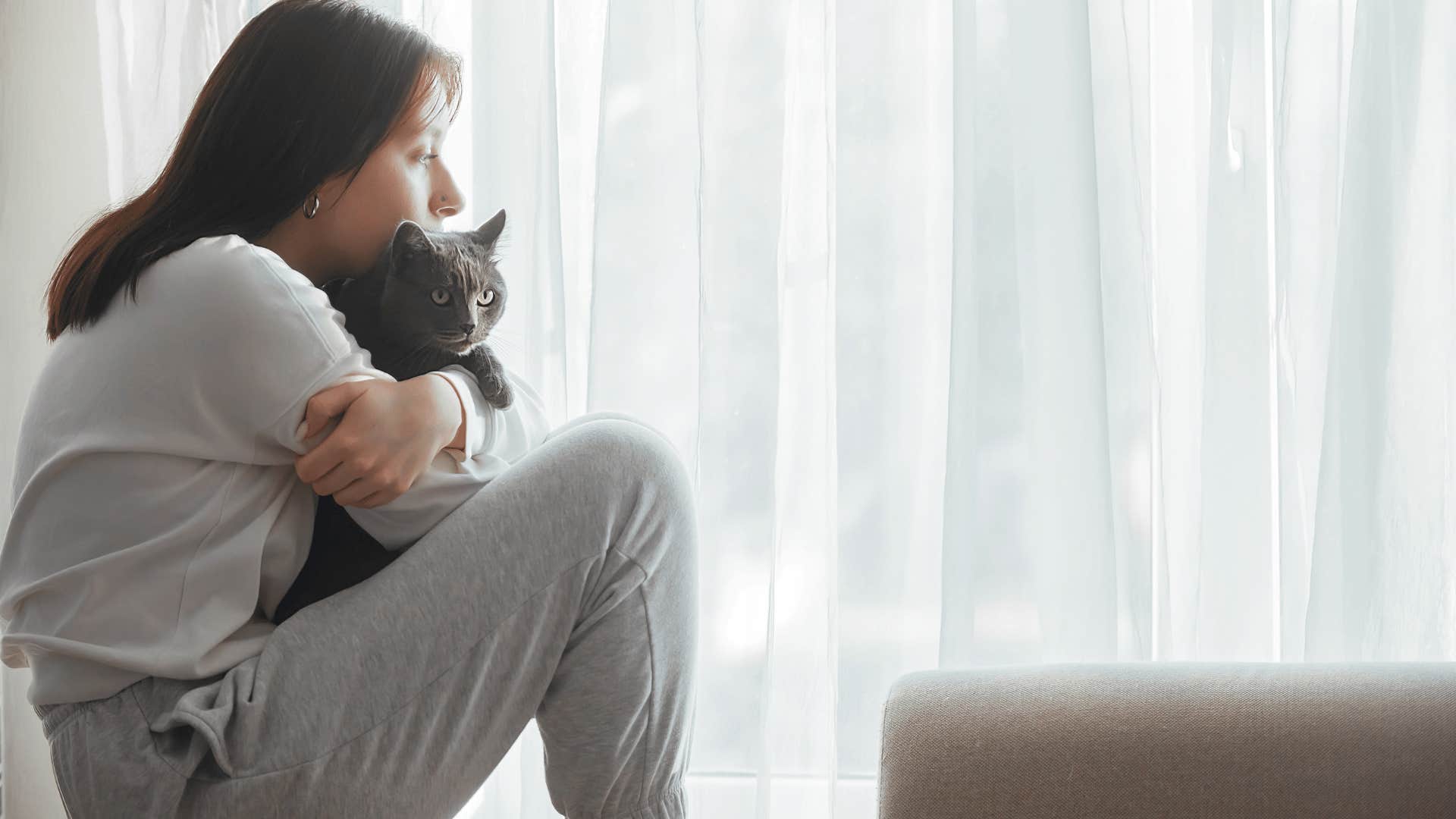 young hugging cat to her chest