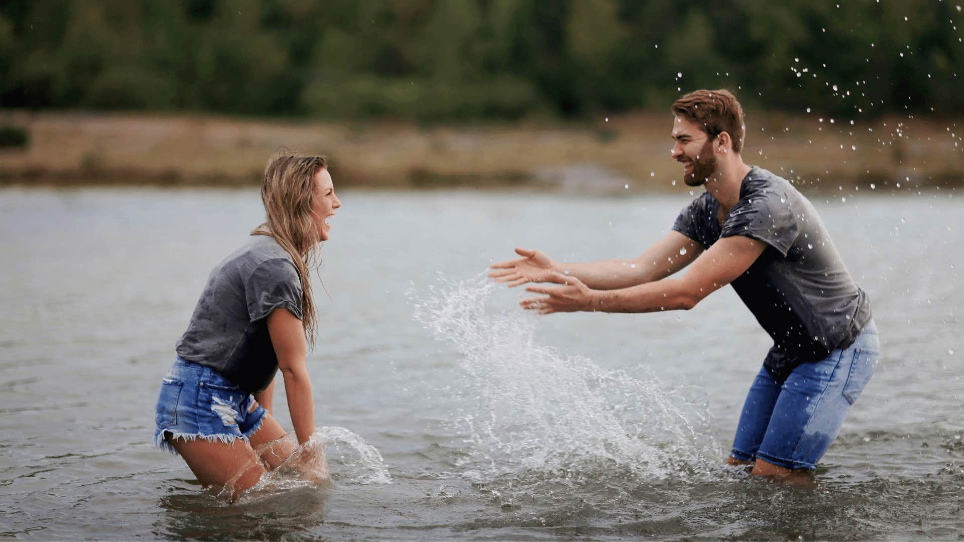 happy couple splashing each other in lake