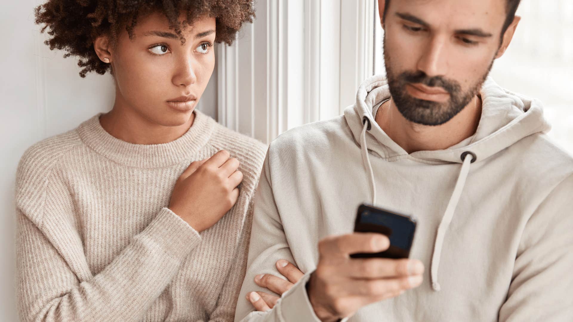 woman being ignored by man using phone