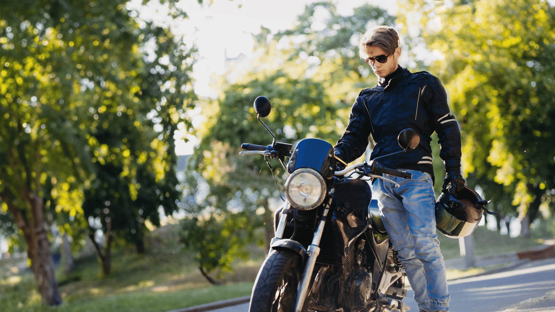 young man standing by motorcycle