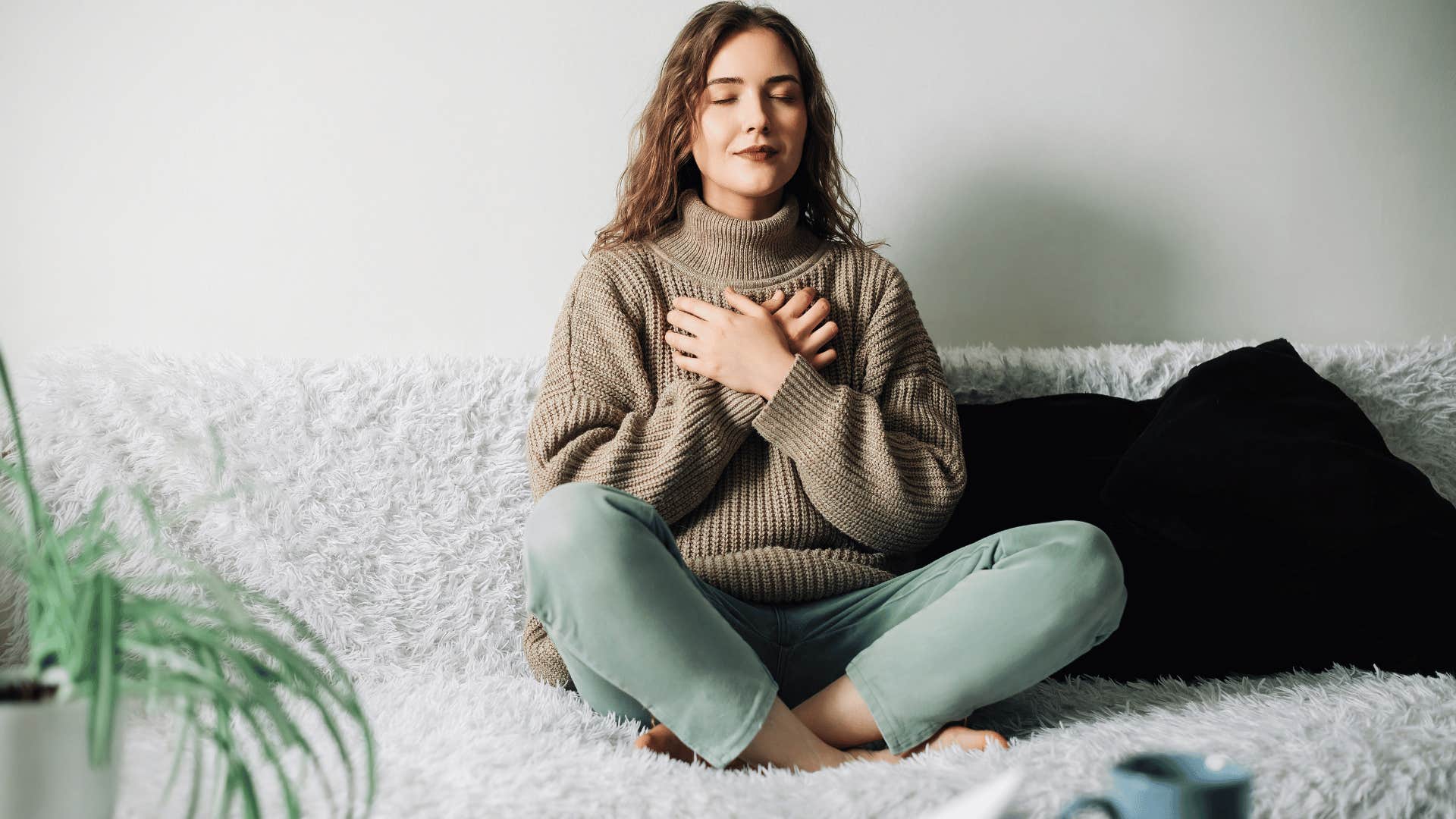 young woman meditating alone on a sofa