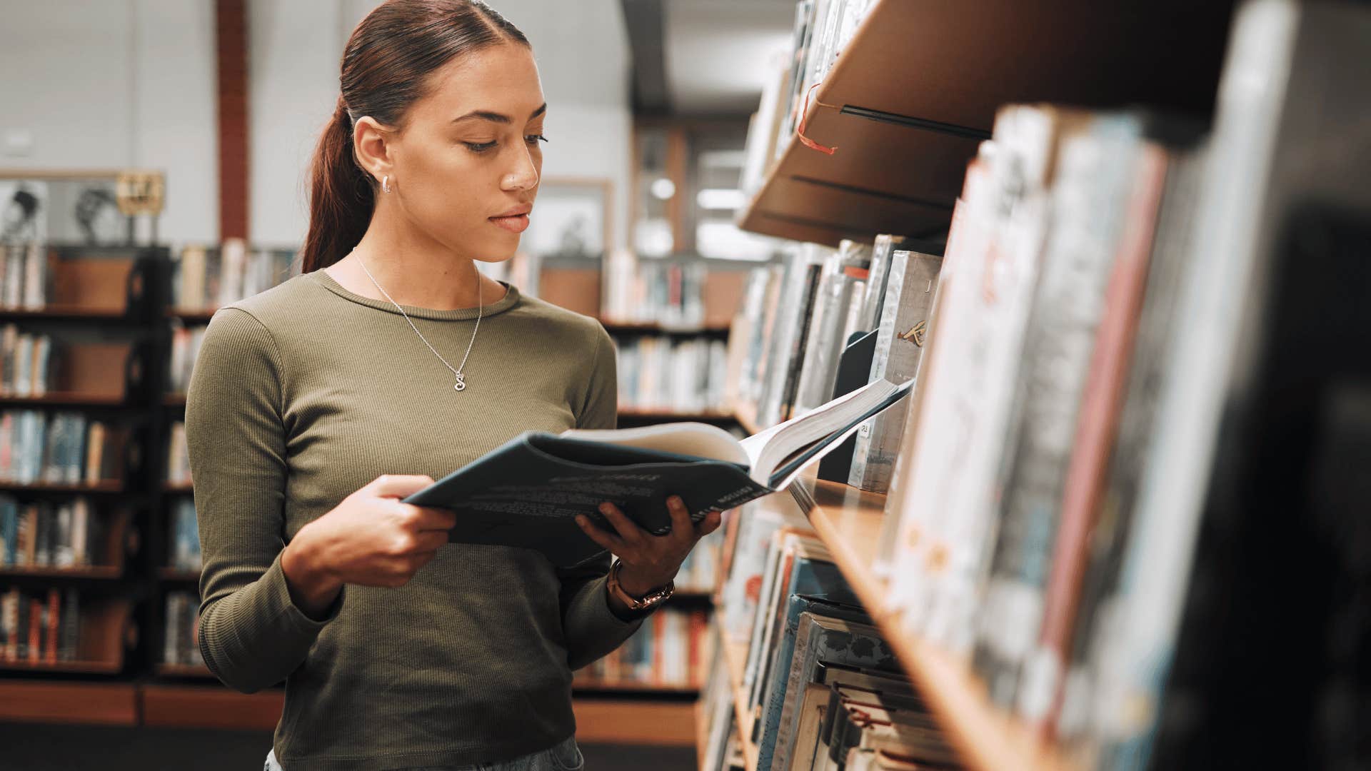 young woman scanning a book in the library