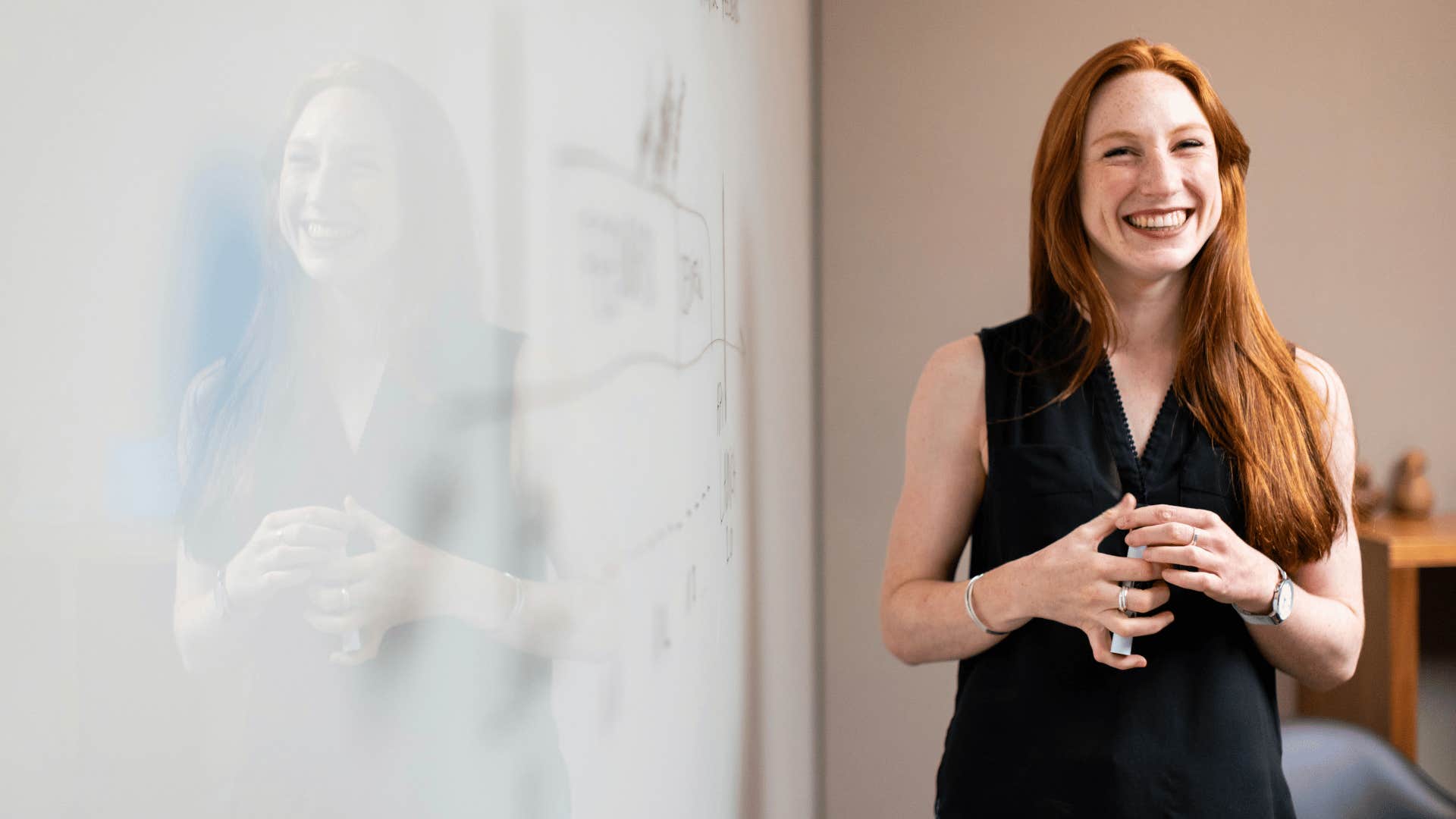 smiling young woman holding a whiteboard marker