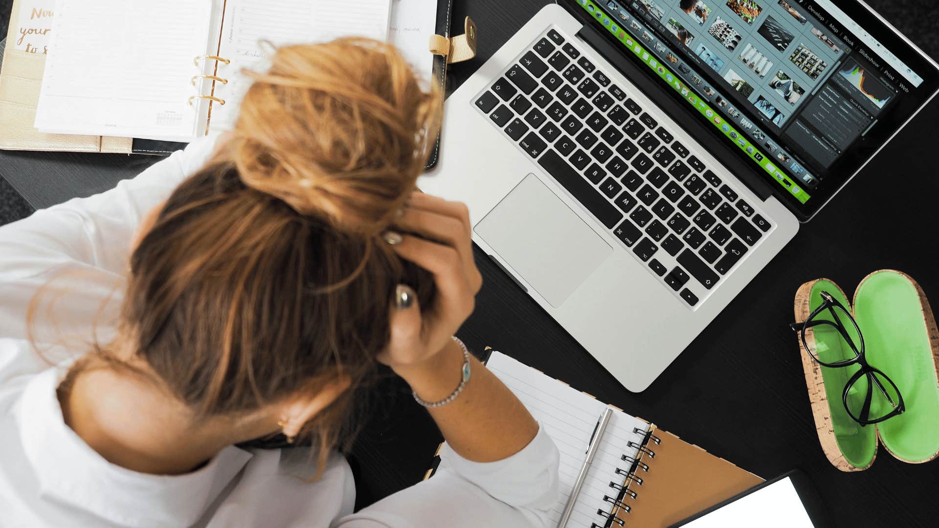 woman's head in her hands with an open laptop