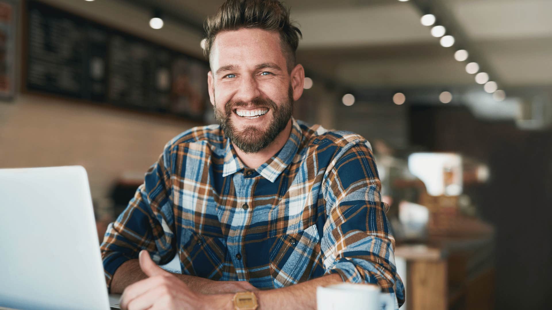 man smiling wide sitting in a cafe