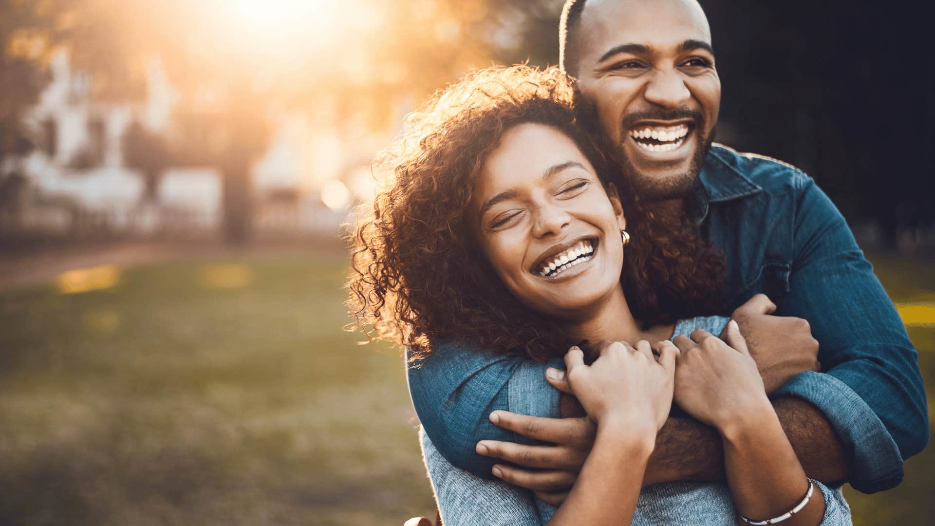 smiling man hugging a woman from behind