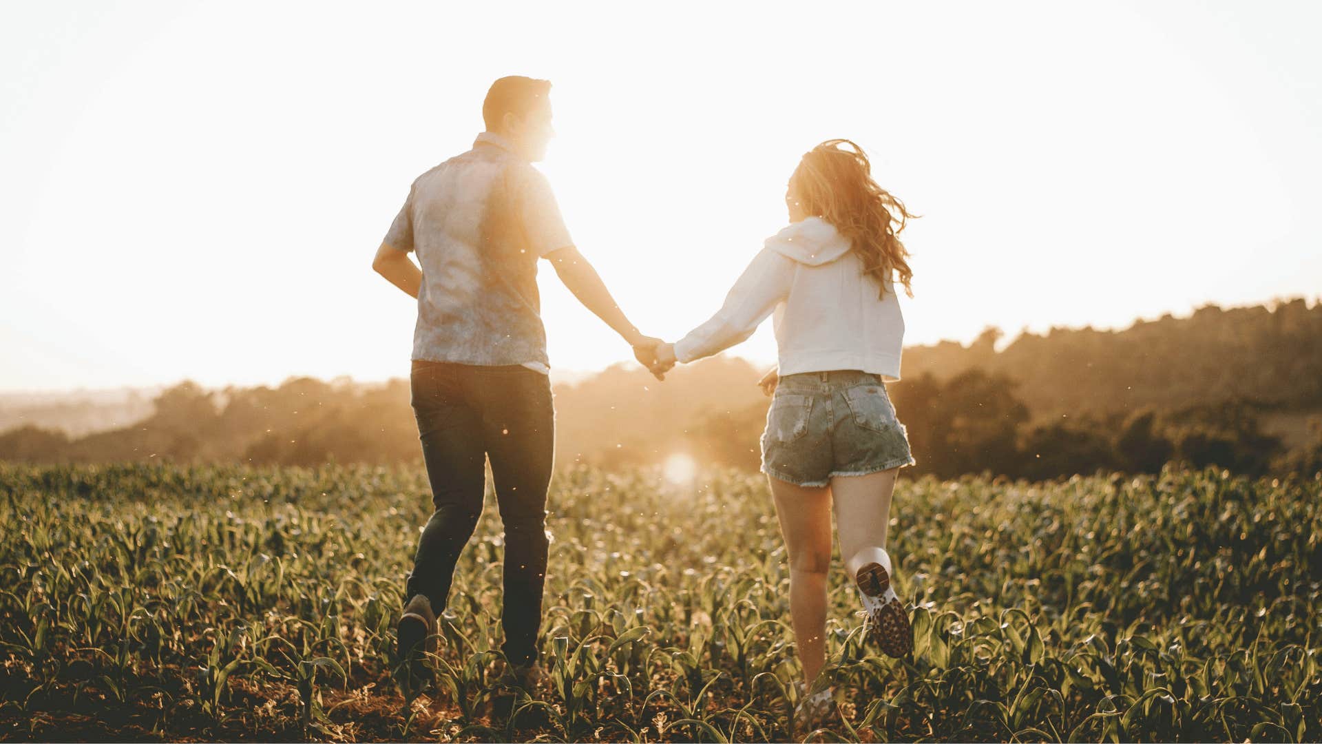 couple running on a field at sunset