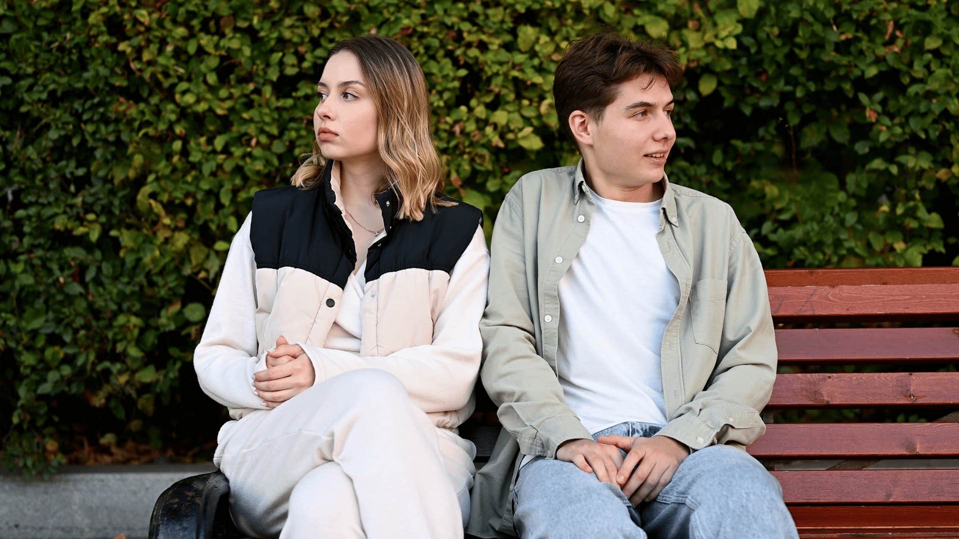 couple sitting awkwardly on park bench