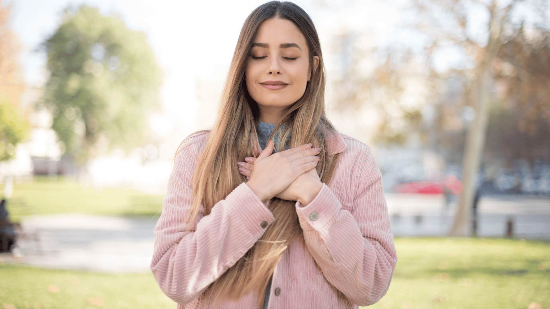 young woman with hands on her hand showing kindness to herself